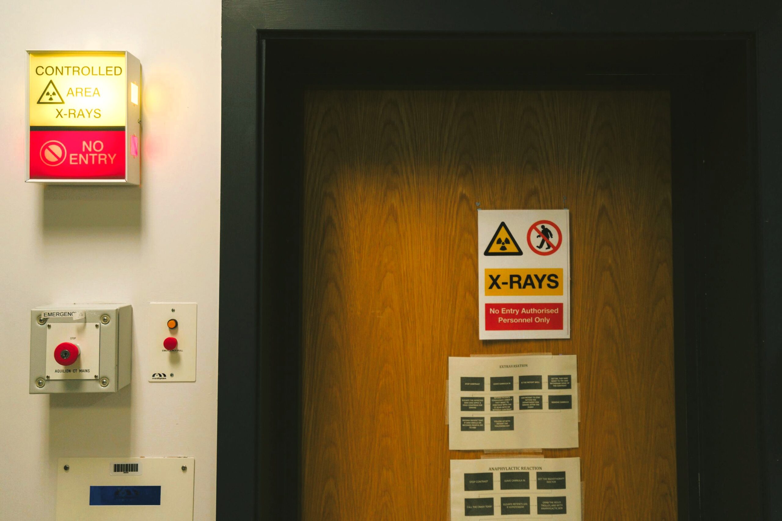 Eingang zu einem Bereich mit Schild „X-RAYS“ und Warnhinweisen (inkl. „Don’t Enter“/„Controlled Area“), daneben ein Kontroll- bzw. Bedienpanel mit Schaltern und Anzeigen.